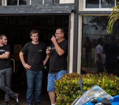 Three men standing at the front of the creative workshop wearing branded shirts for the company